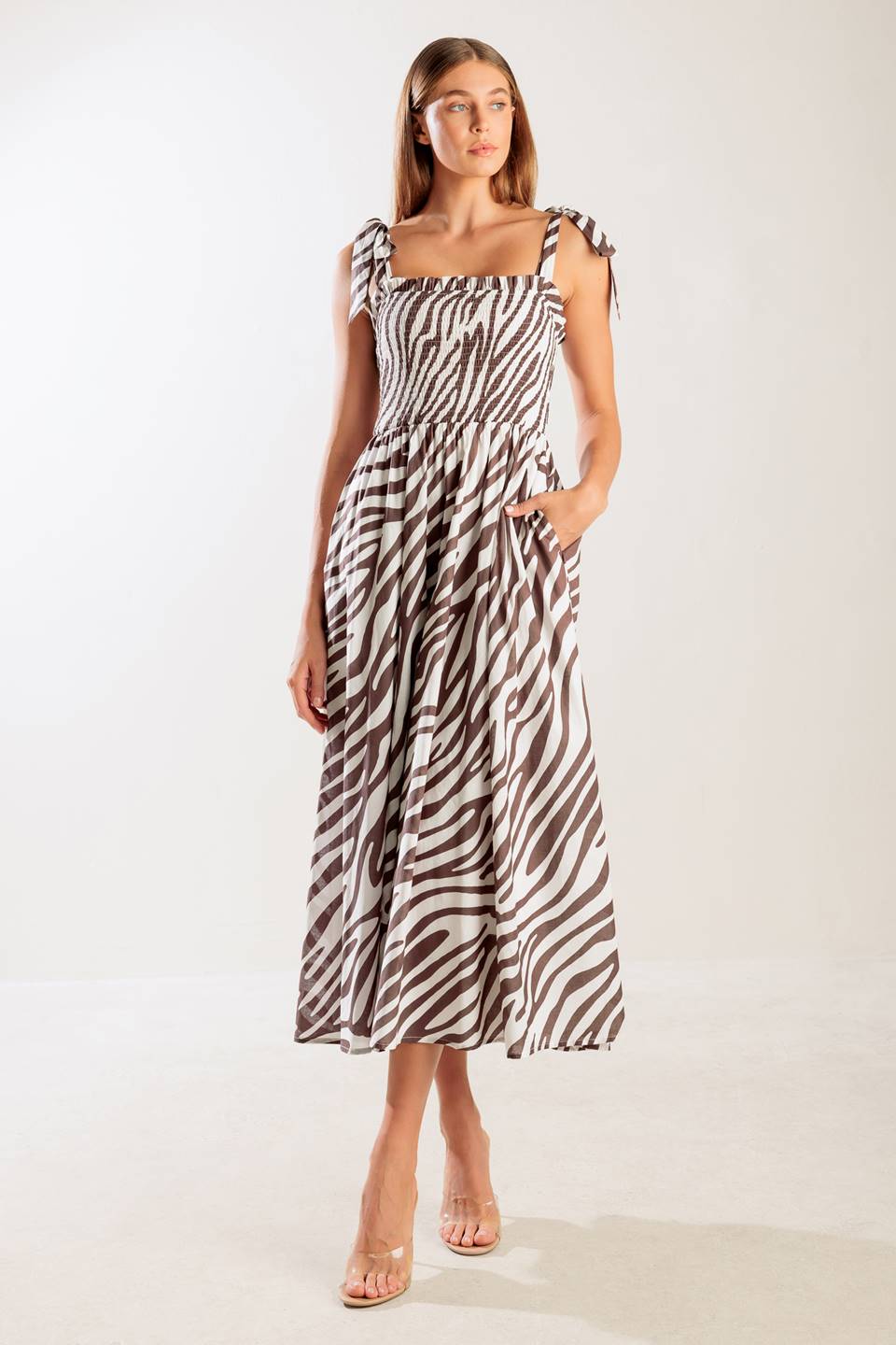 A printed woven midi dress featuring straight neckline with ruffled edge, shoulder tie, smocked bodice and full skirt