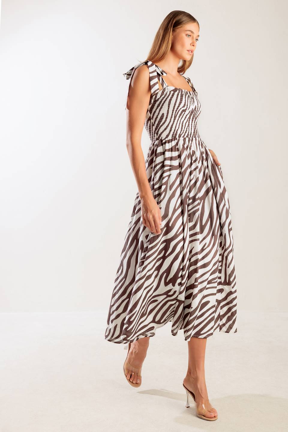 A printed woven midi dress featuring straight neckline with ruffled edge, shoulder tie, smocked bodice and full skirt