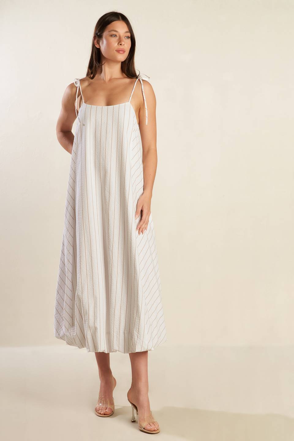 A striped woven midi dress featuring cami top with shoulder ties, bubble hem and button back.