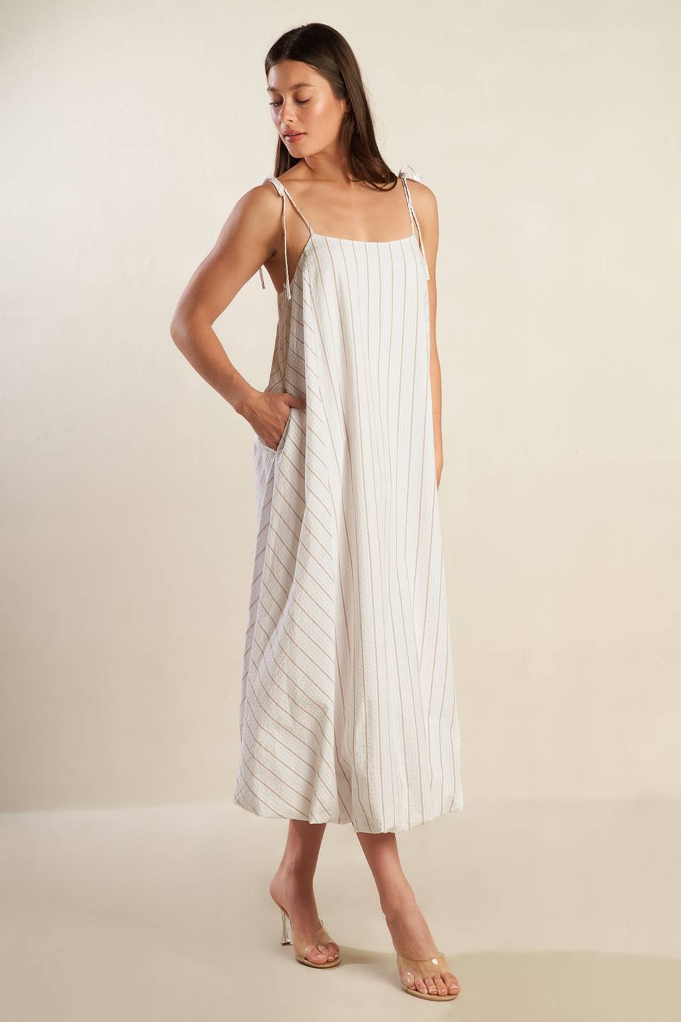 A striped woven midi dress featuring cami top with shoulder ties, bubble hem and button back.