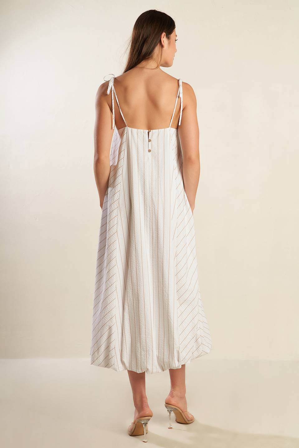 A striped woven midi dress featuring cami top with shoulder ties, bubble hem and button back.