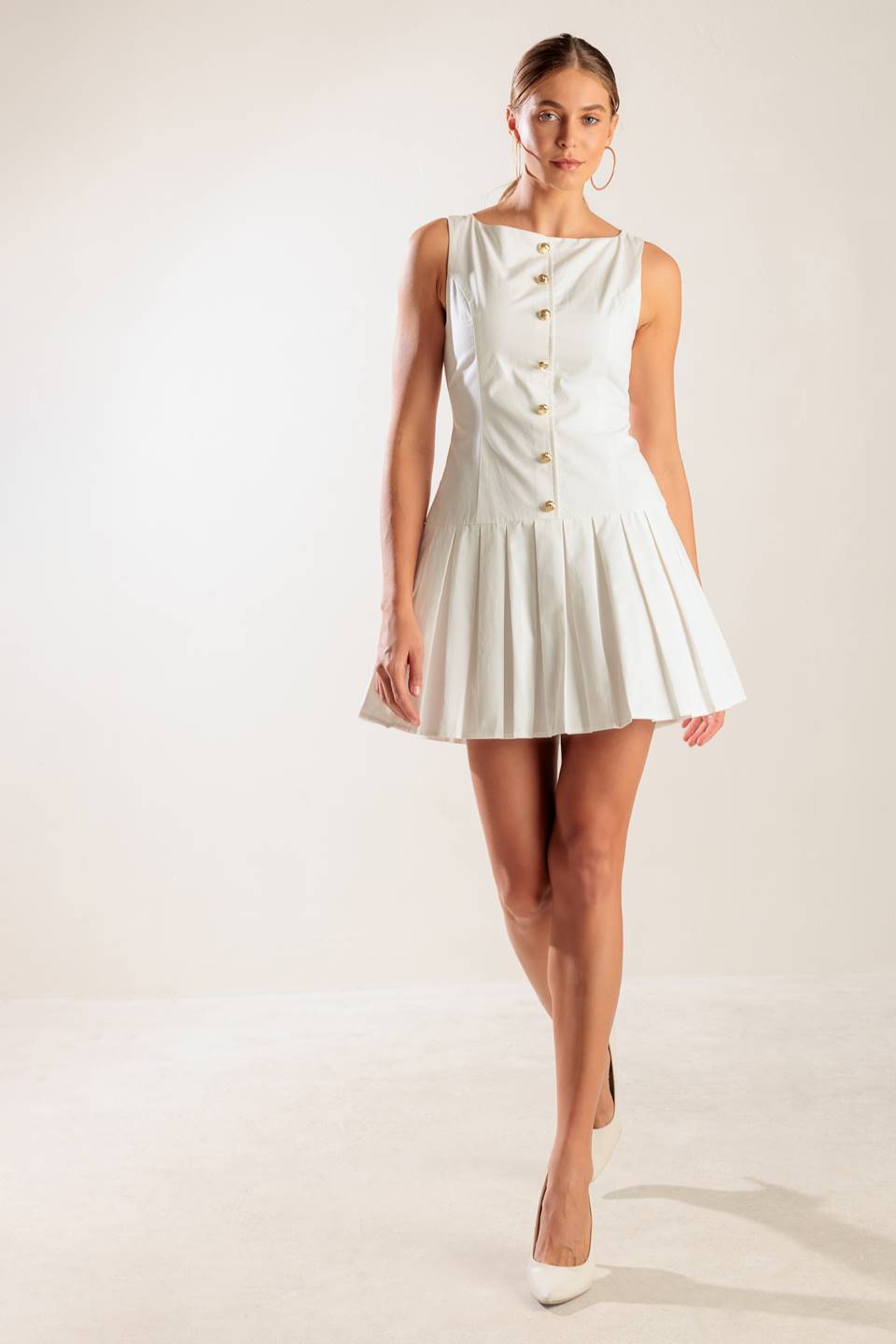 A solid white woven mini dress featuring square neckline, sleeveless, button down detail, box pleated skirt and back zipper closure