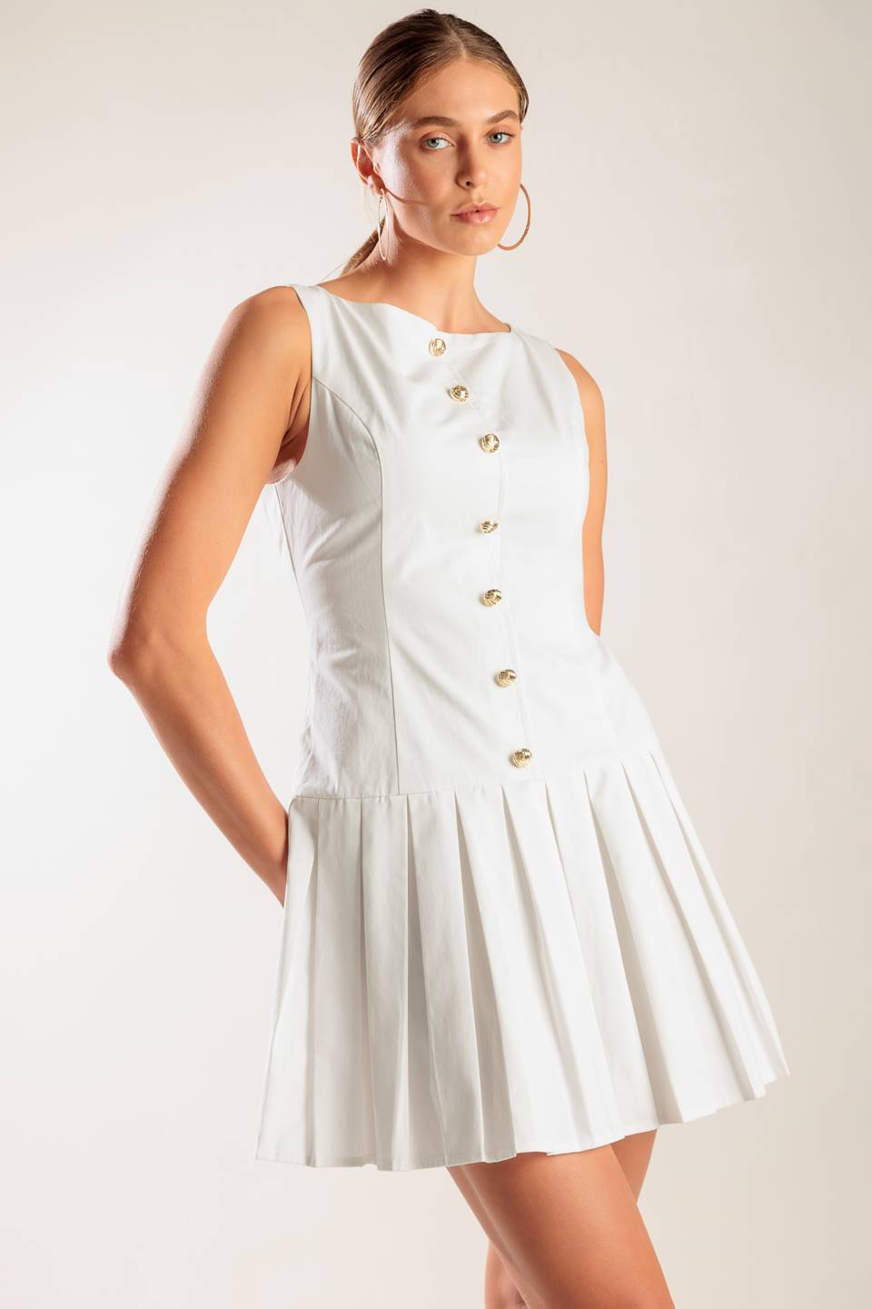 A solid white woven mini dress featuring square neckline, sleeveless, button down detail, box pleated skirt and back zipper closure