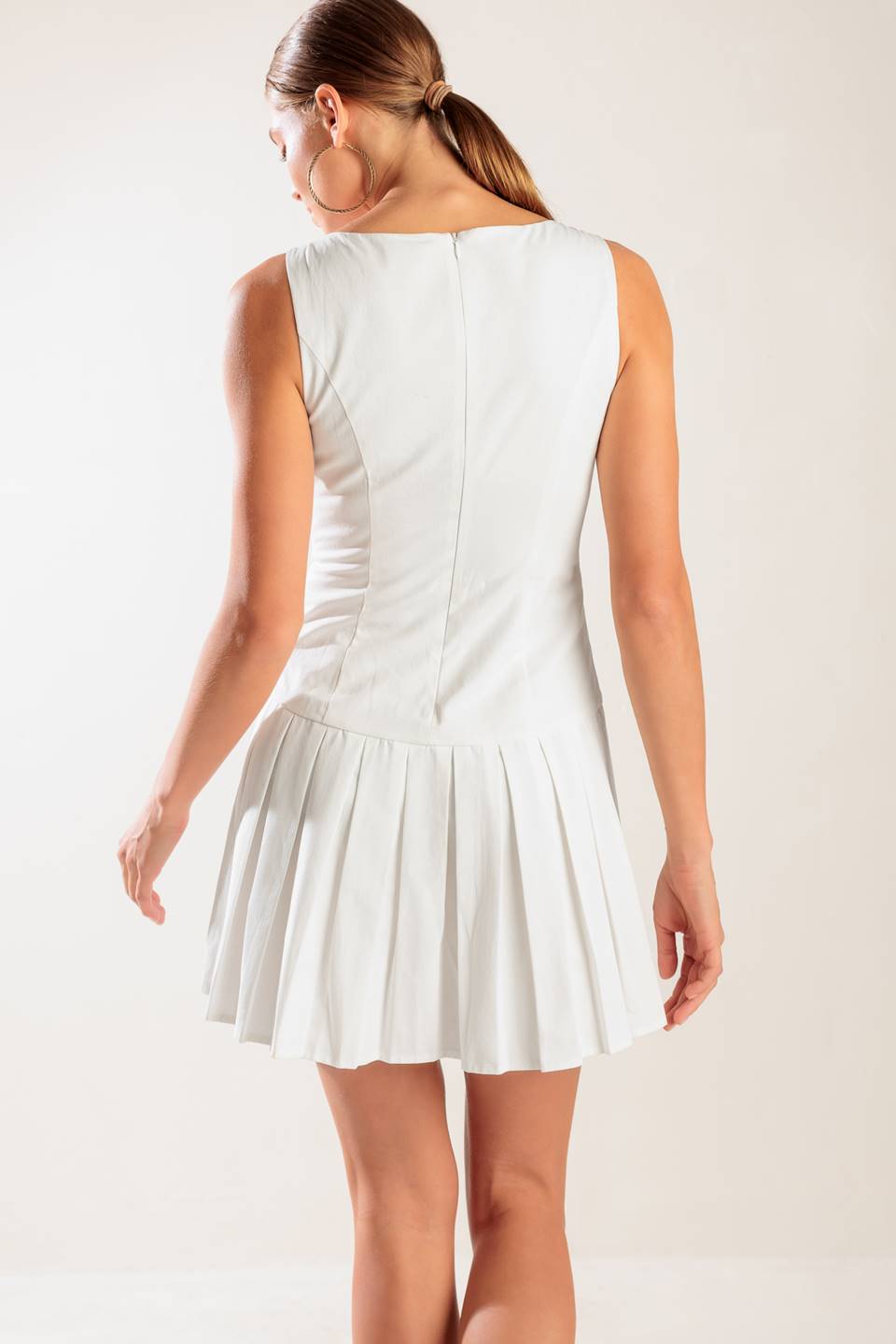 A solid white woven mini dress featuring square neckline, sleeveless, button down detail, box pleated skirt and back zipper closure