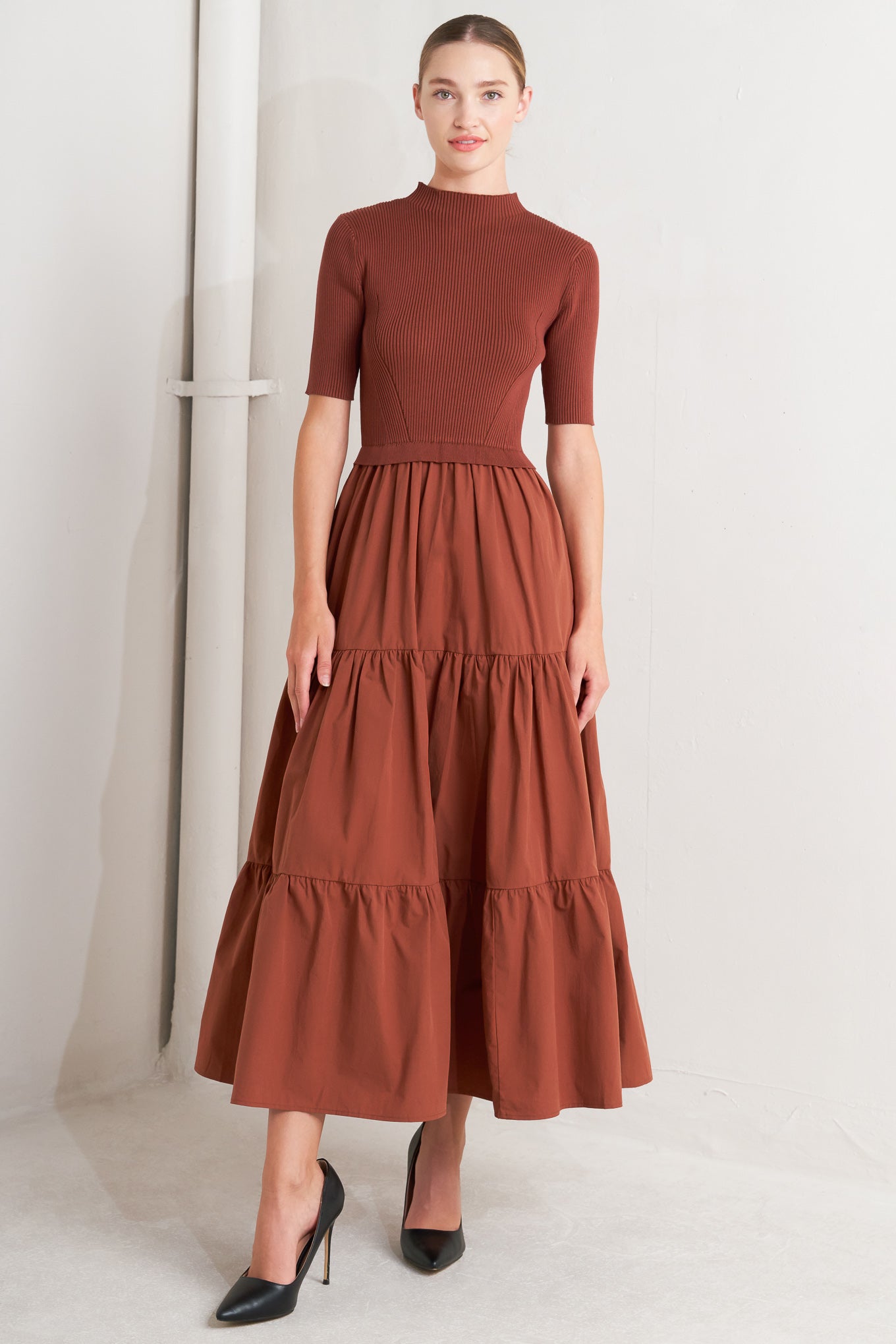 A sweater knit and woven combination midi dress featuring ribbed top with high neckline and short sleeve and tiered woven skirt