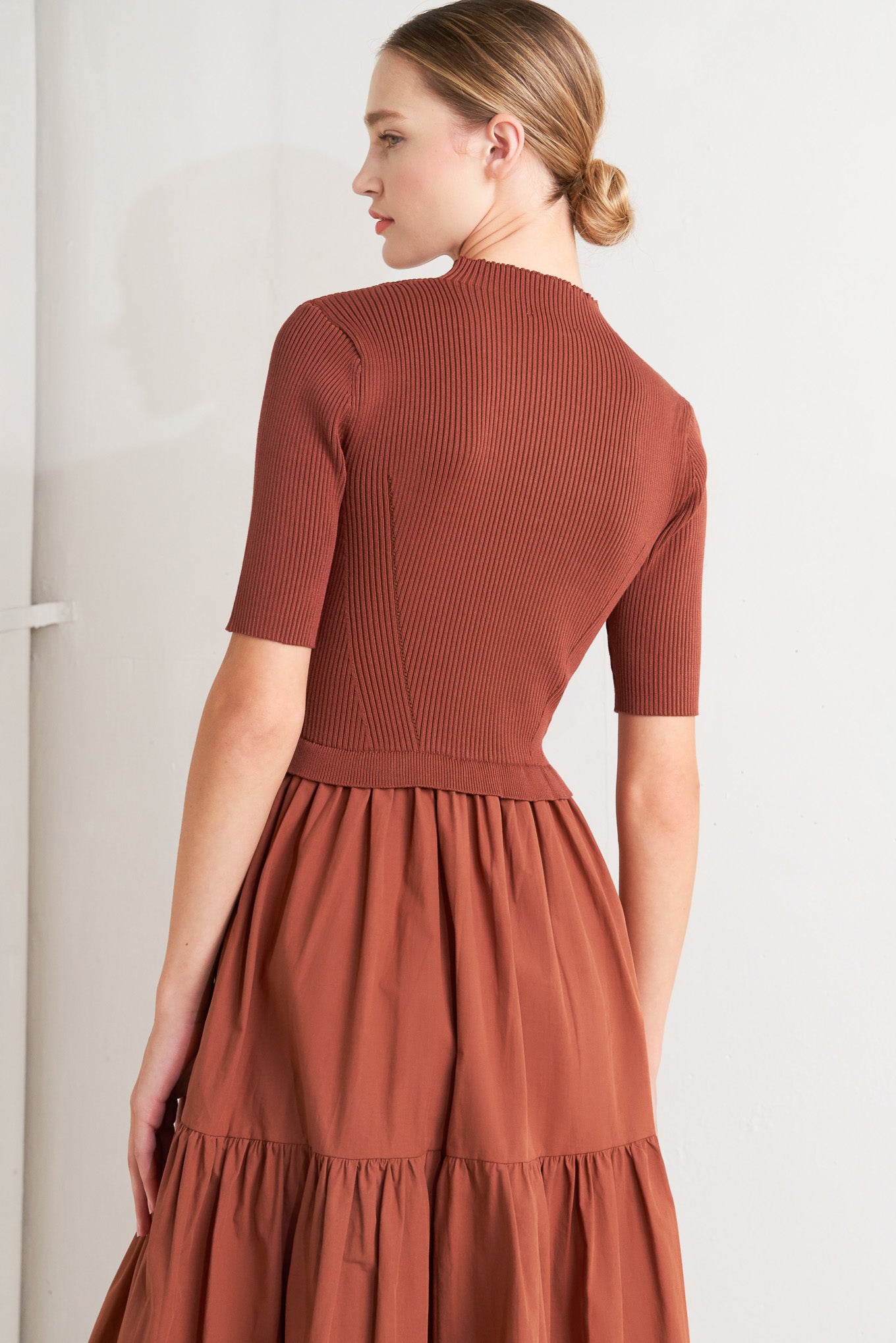 A sweater knit and woven combination midi dress featuring ribbed top with high neckline and short sleeve and tiered woven skirt