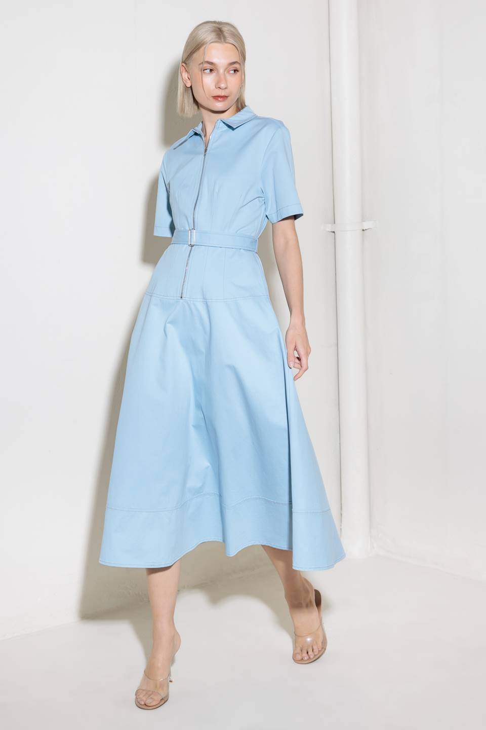 A solid woven shirt dress featuring collar, short sleeve, self belt, circle skirt and front zipper closure.
