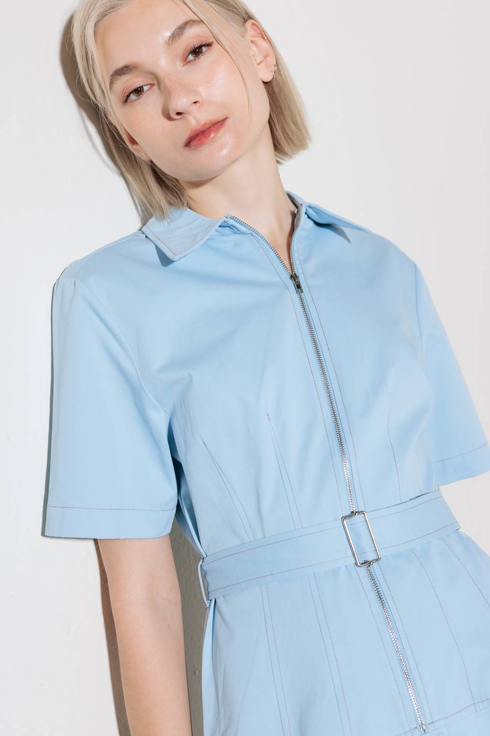 A solid woven shirt dress featuring collar, short sleeve, self belt, circle skirt and front zipper closure.
