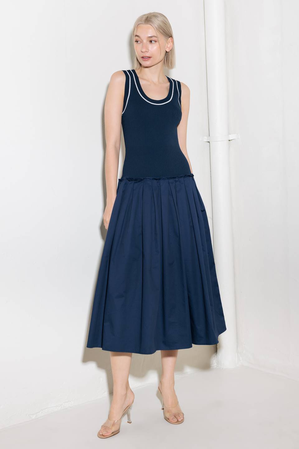 A ribbed sweater knit top and woven skirt combination dress featuring U neckline and sleeveless.