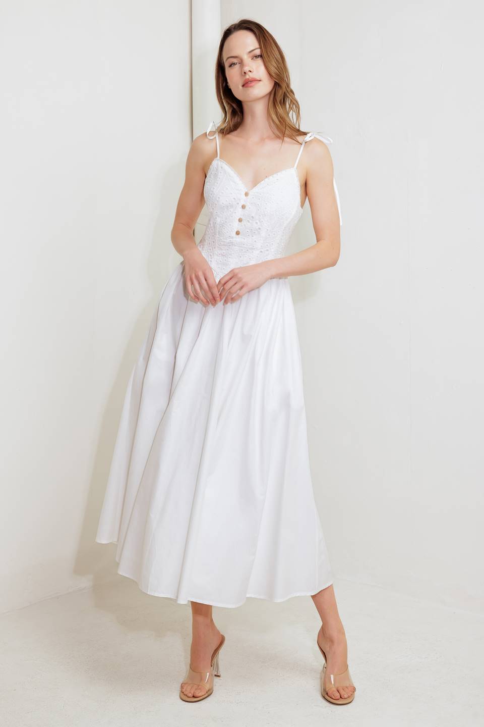 A solid woven midi dress featuring eyelet top with shoulder tie, solid full skirt, low back with zipper closure
