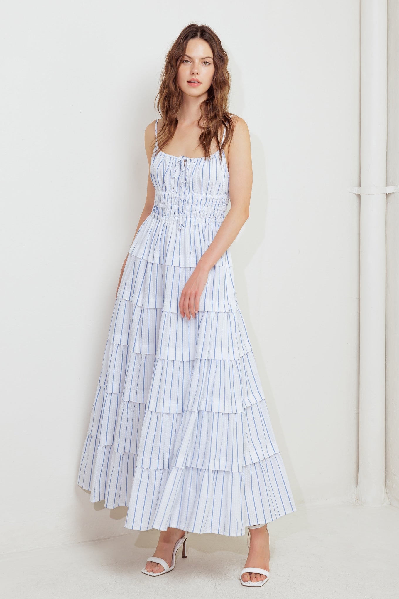A striped woven midi dress featuring shirred top with front tie, smocked waist, tiered skirt and bare back with straps