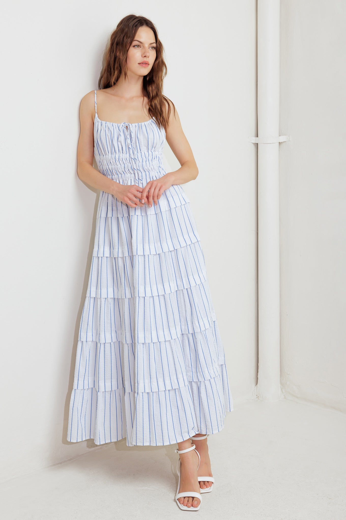 A striped woven midi dress featuring shirred top with front tie, smocked waist, tiered skirt and bare back with straps