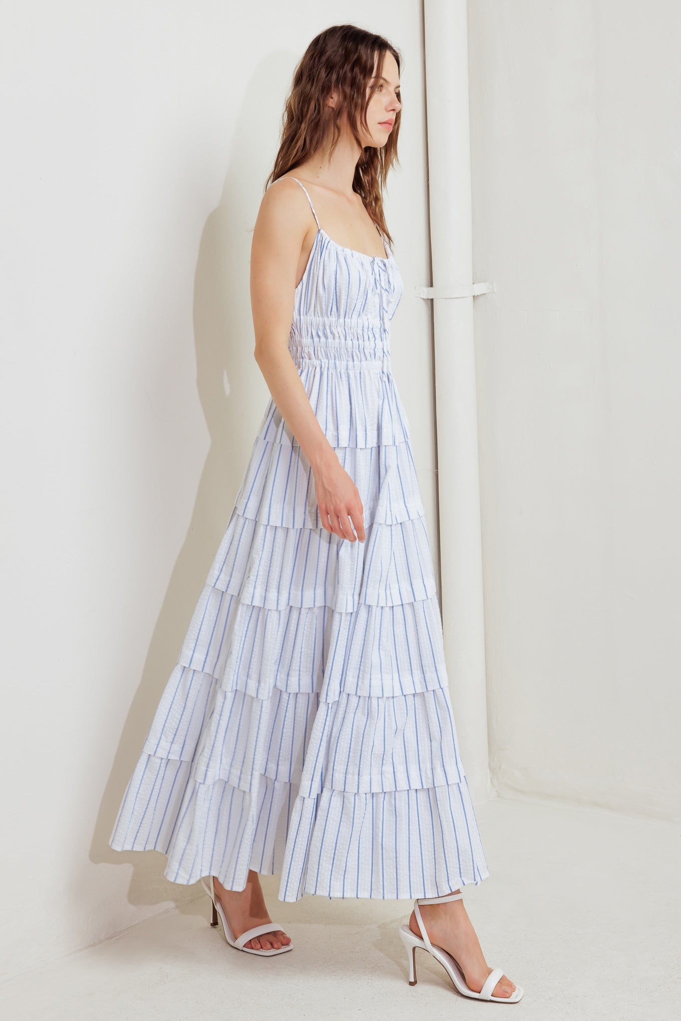 A striped woven midi dress featuring shirred top with front tie, smocked waist, tiered skirt and bare back with straps