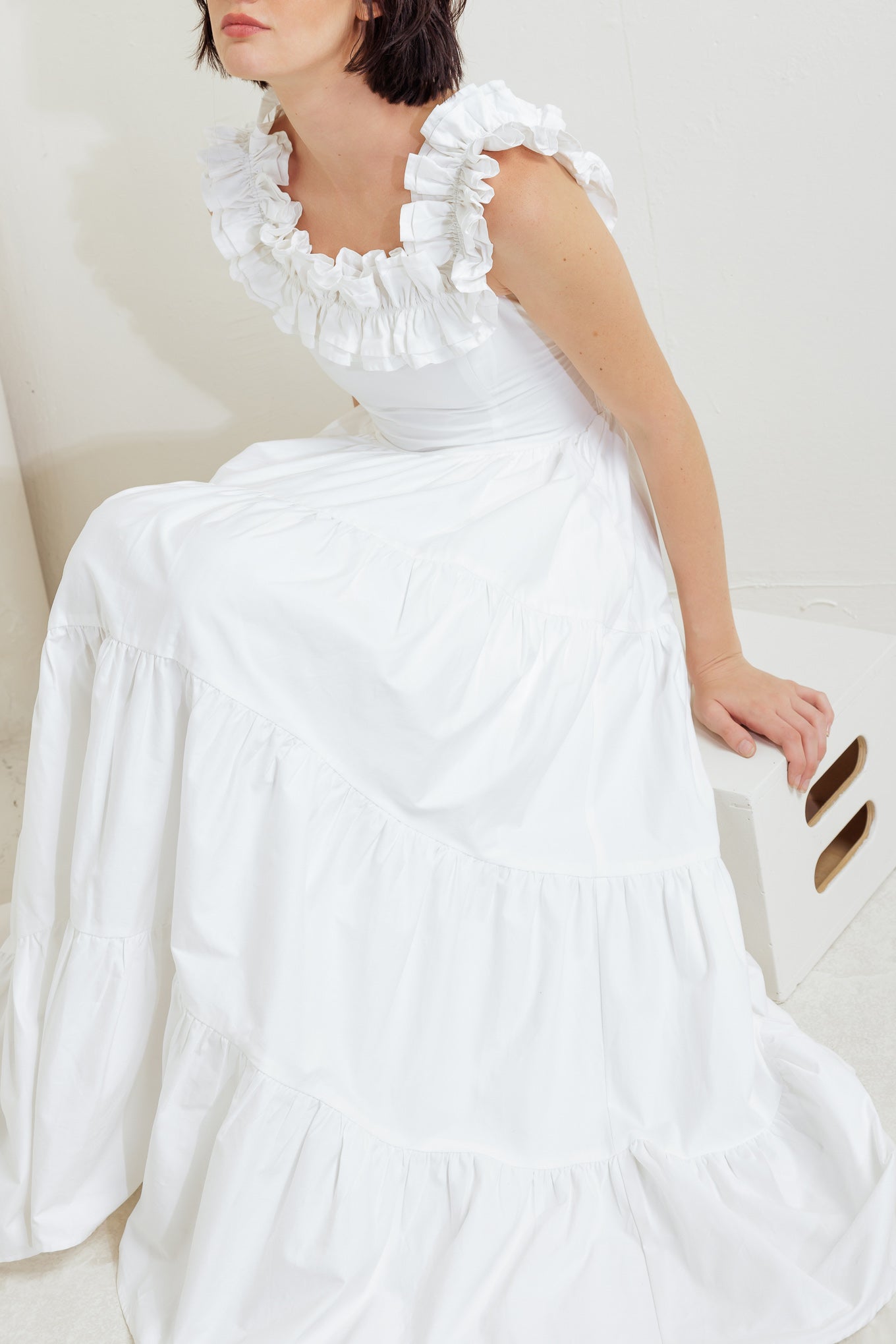 A solid woven midi dress featuring ruffled neckline, tiered skirt, smocked back bodice and tie closure