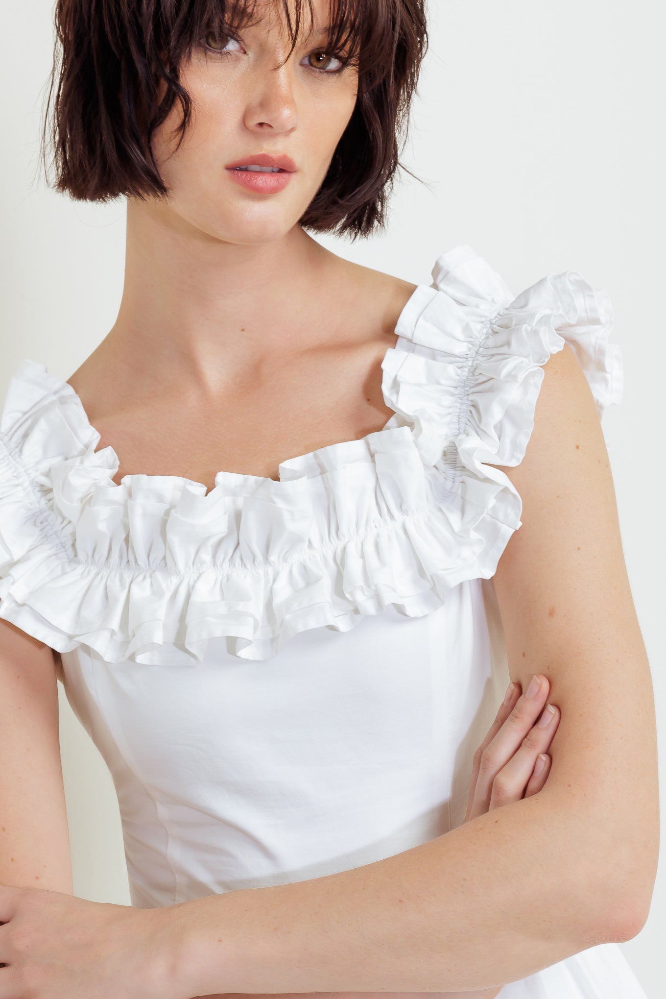 A solid woven midi dress featuring ruffled neckline, tiered skirt, smocked back bodice and tie closure