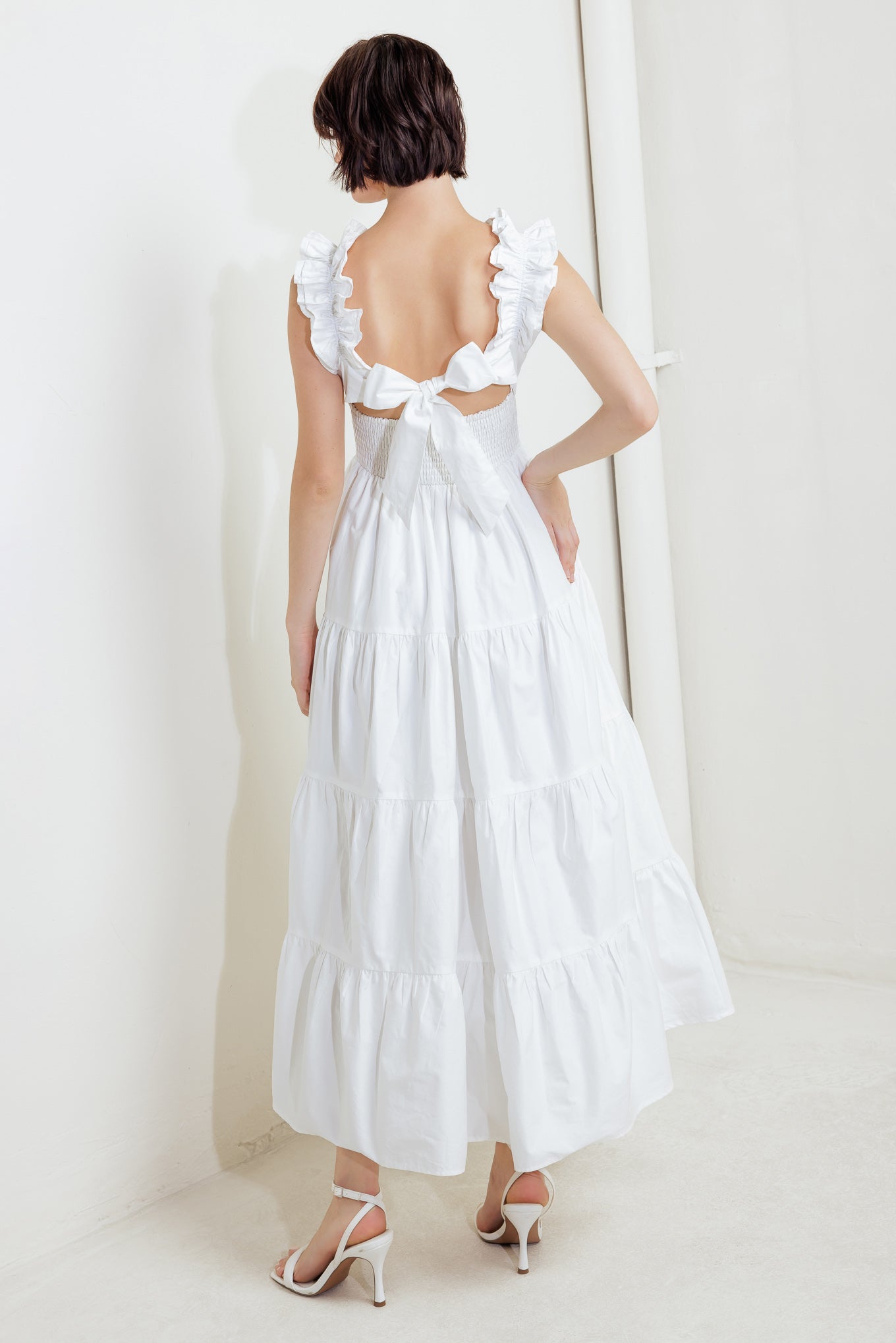 A solid woven midi dress featuring ruffled neckline, tiered skirt, smocked back bodice and tie closure