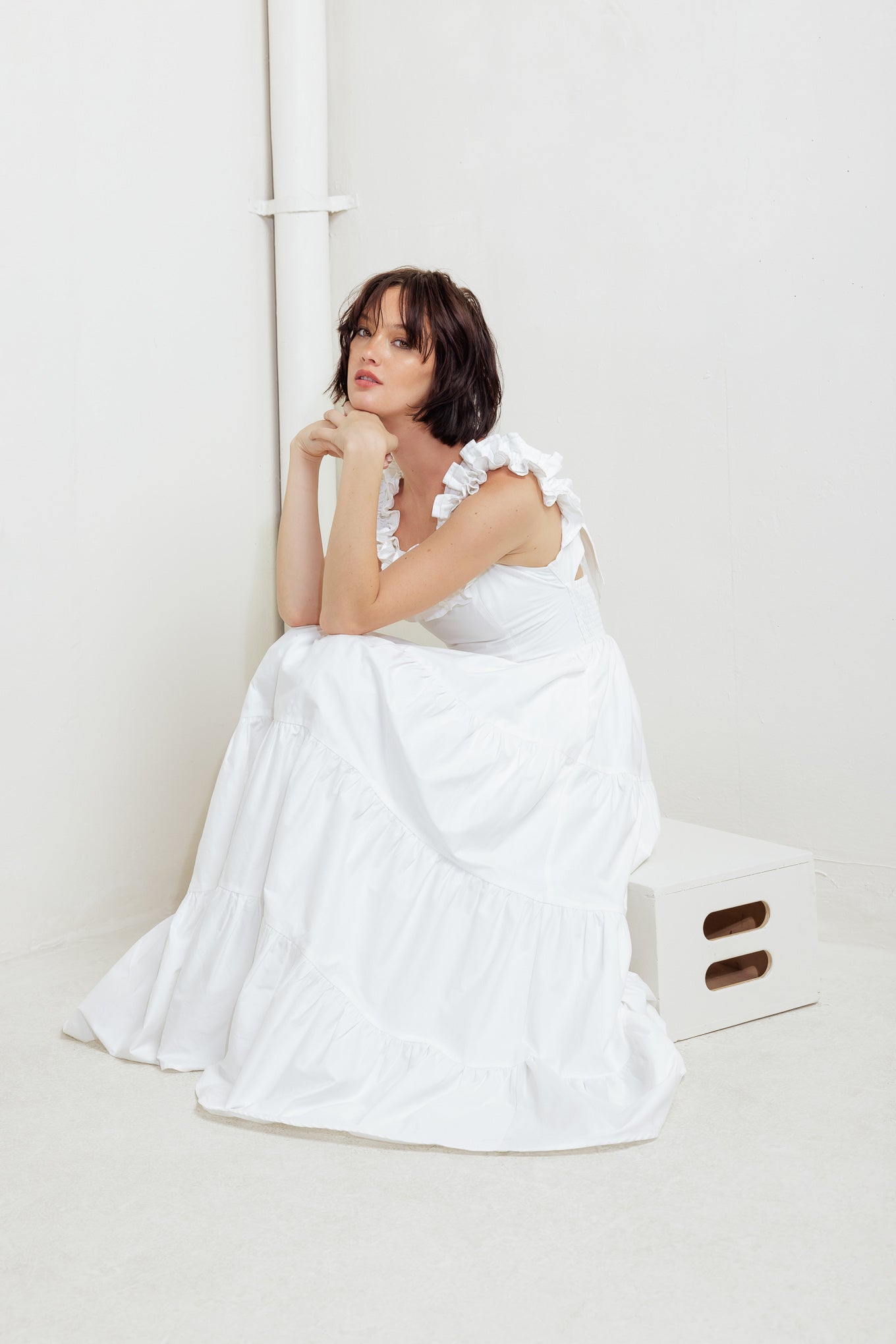 A solid woven midi dress featuring ruffled neckline, tiered skirt, smocked back bodice and tie closure