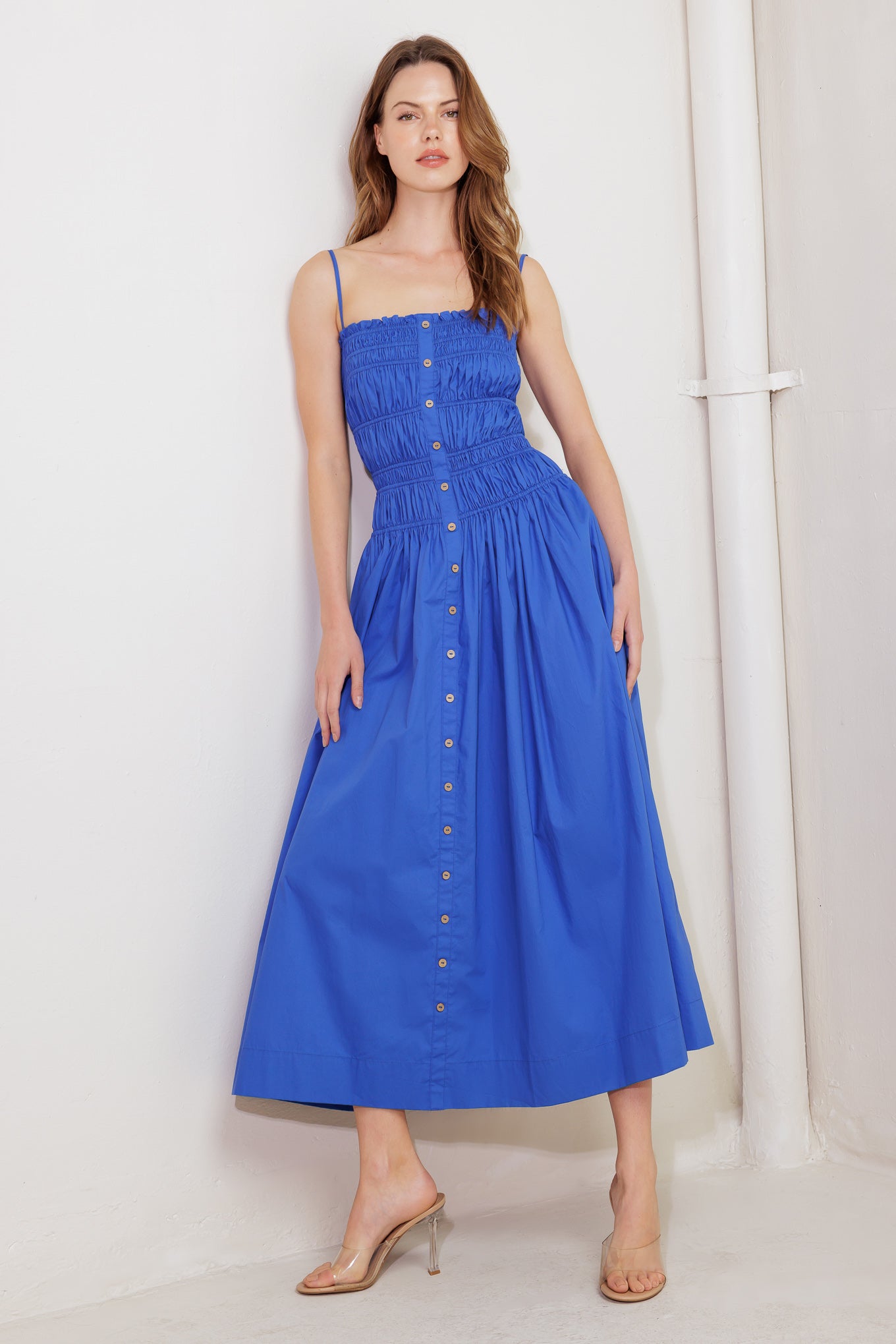 A solid blue woven midi dress featuring straight neckline, straps, button down detail and smocked bodice