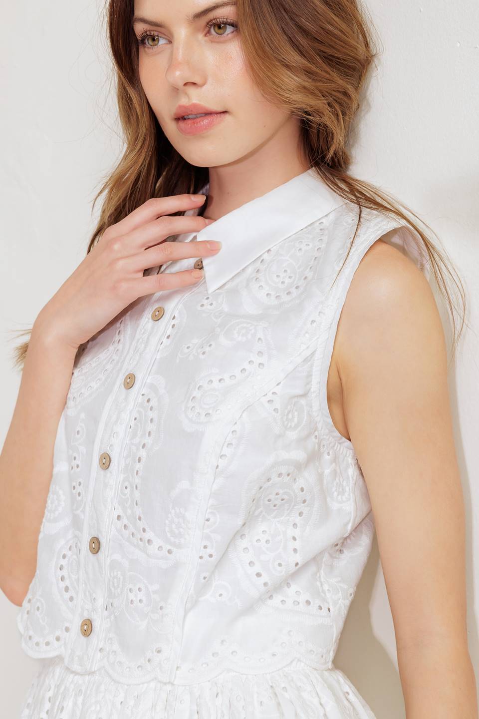 A woven eyelet mini dress featuring pop over, collar, button down, sleeveless and back zipper closure