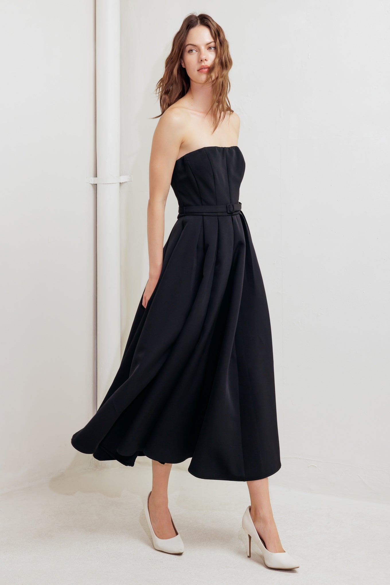 A solid woven midi dress featuring strapless straight neckline, self belt, full skirt and back zipper closure