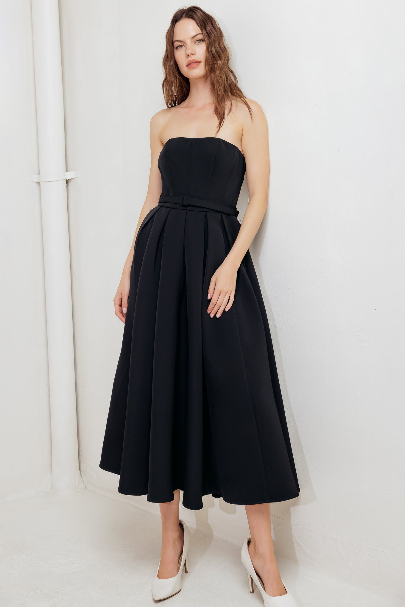 A solid woven midi dress featuring strapless straight neckline, self belt, full skirt and back zipper closure