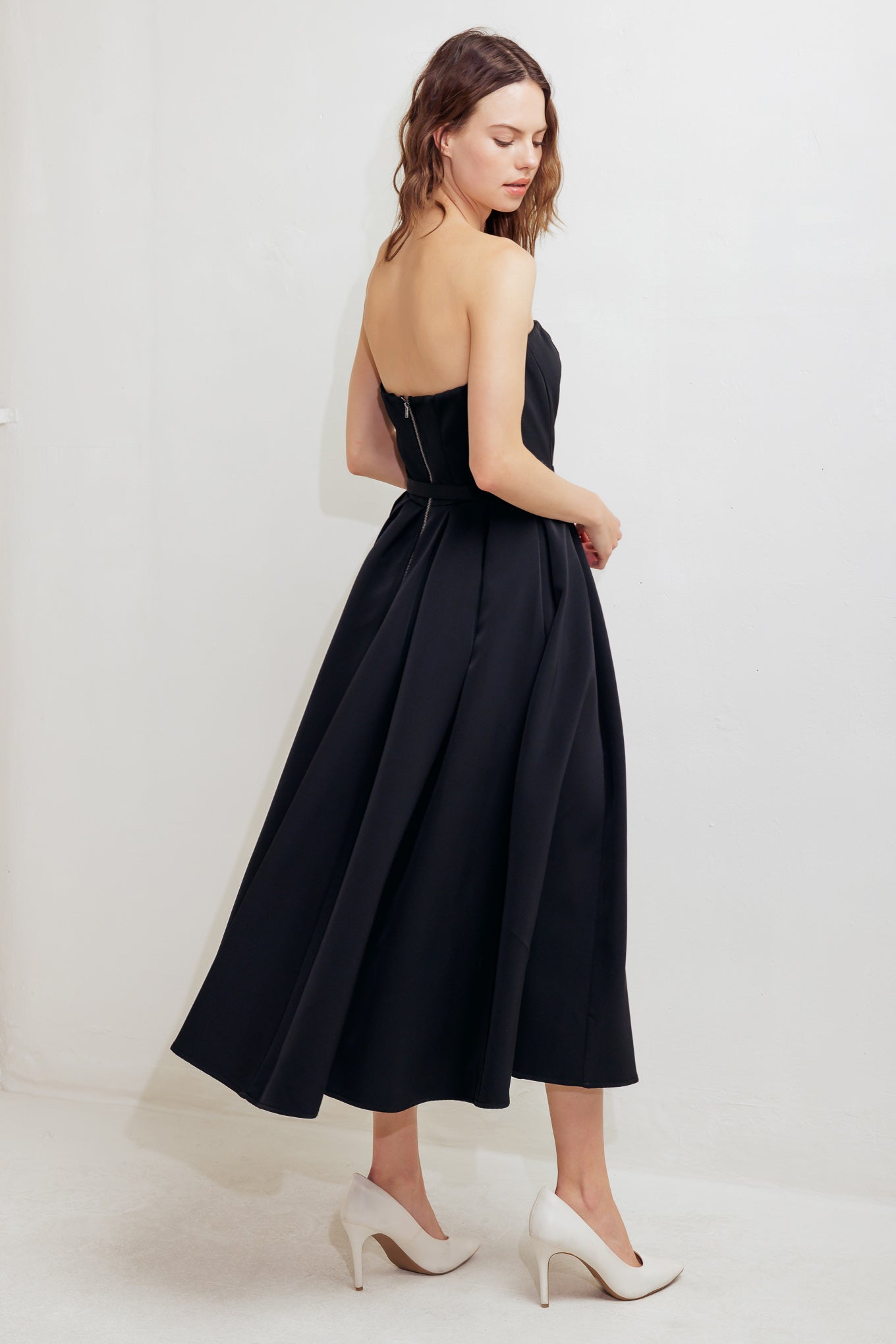 A solid woven midi dress featuring strapless straight neckline, self belt, full skirt and back zipper closure