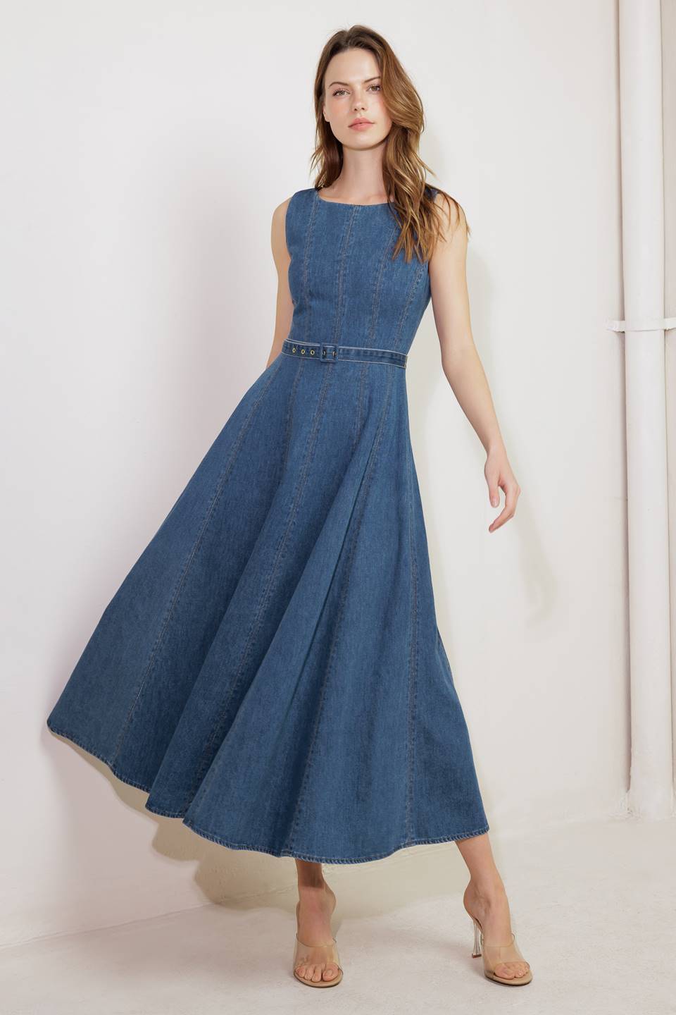 A washed denim midi dress featuring boat neckline, sleeveless, self belt, circle skirt and back zipper closure