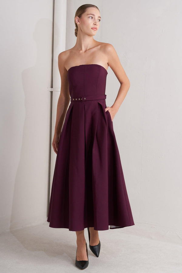 A solid woven mid dress featuring strapless, self belt, full skirt and back zipper closure