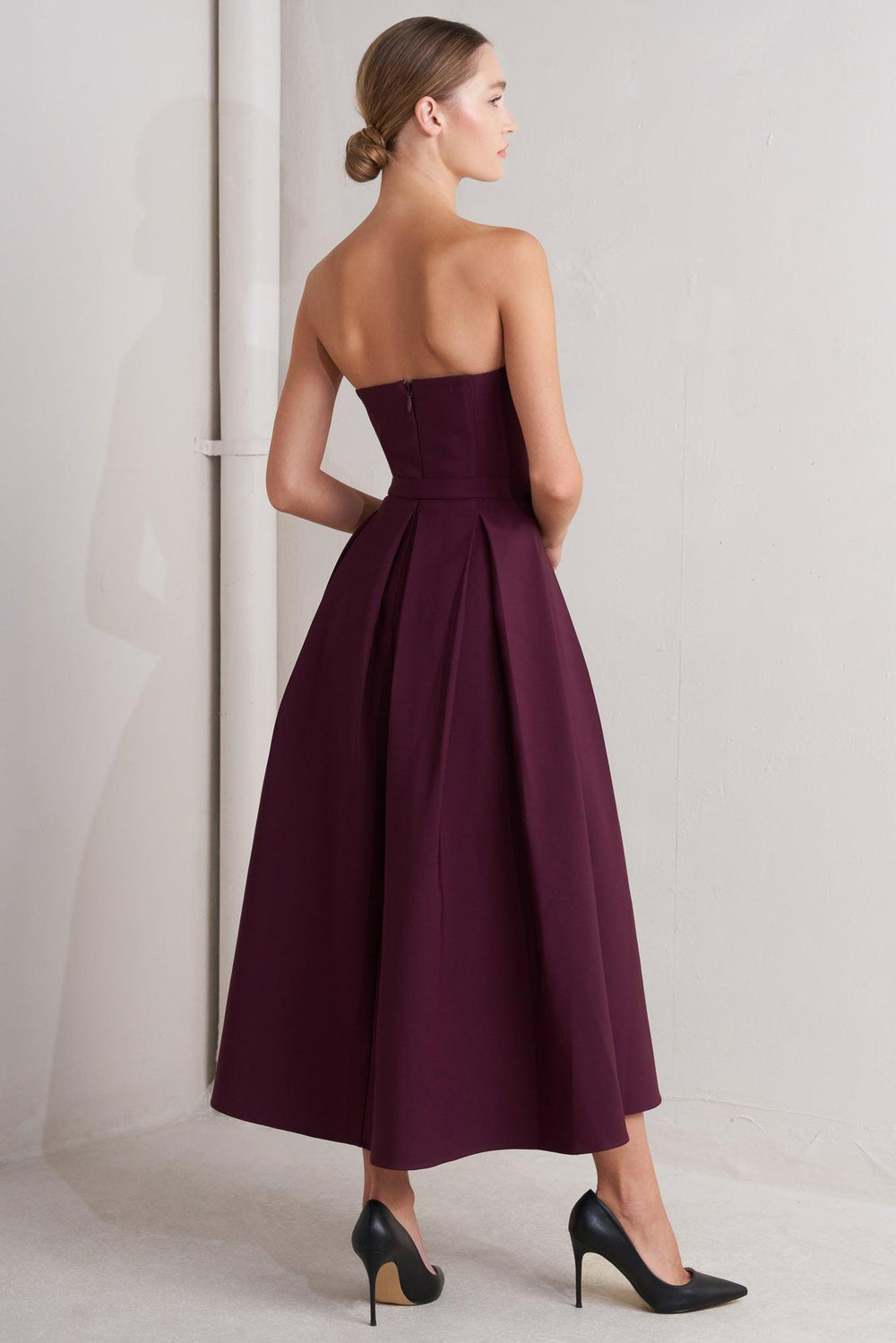 A solid woven mid dress featuring strapless, self belt, full skirt and back zipper closure