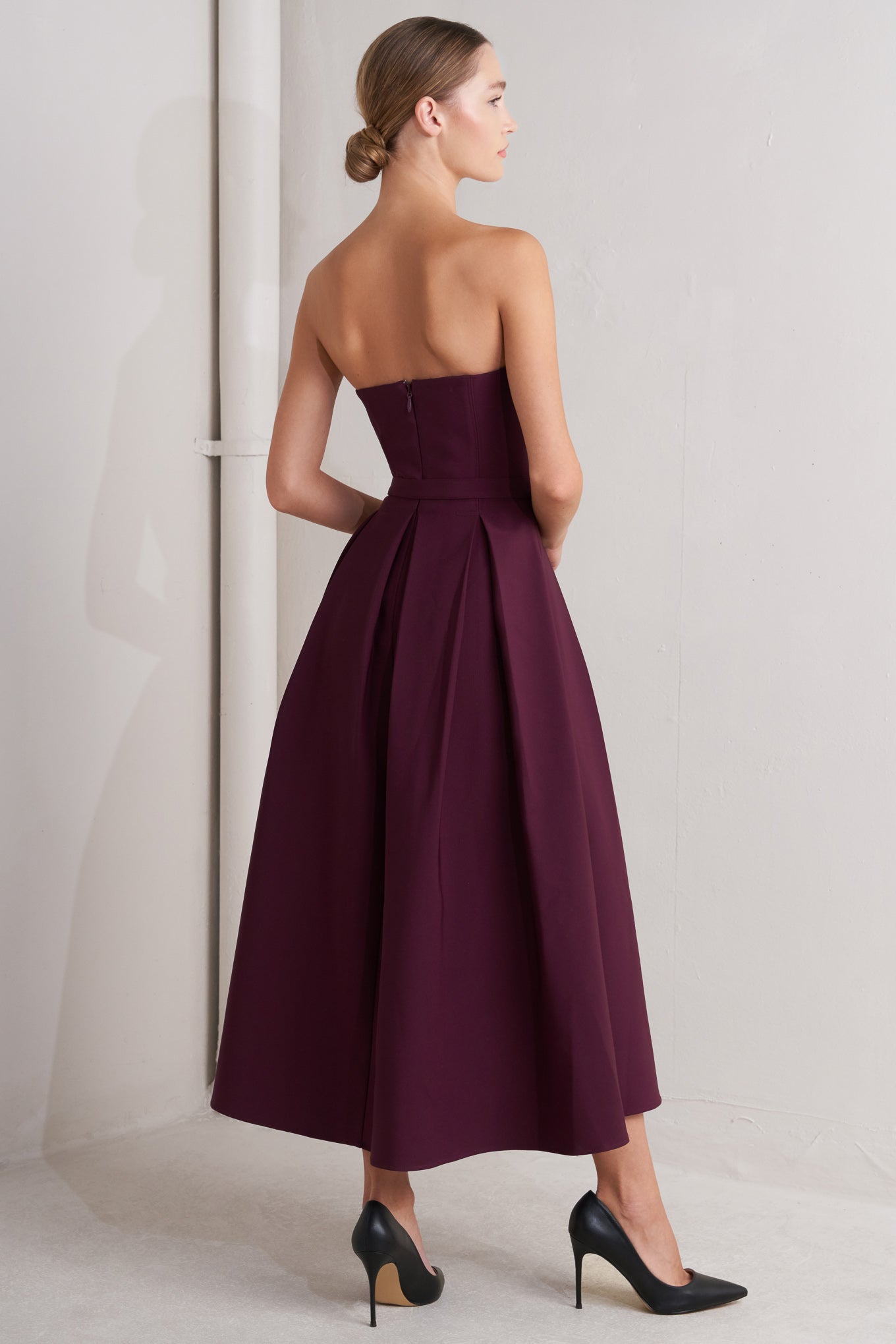 A solid woven mid dress featuring strapless, self belt, full skirt and back zipper closure