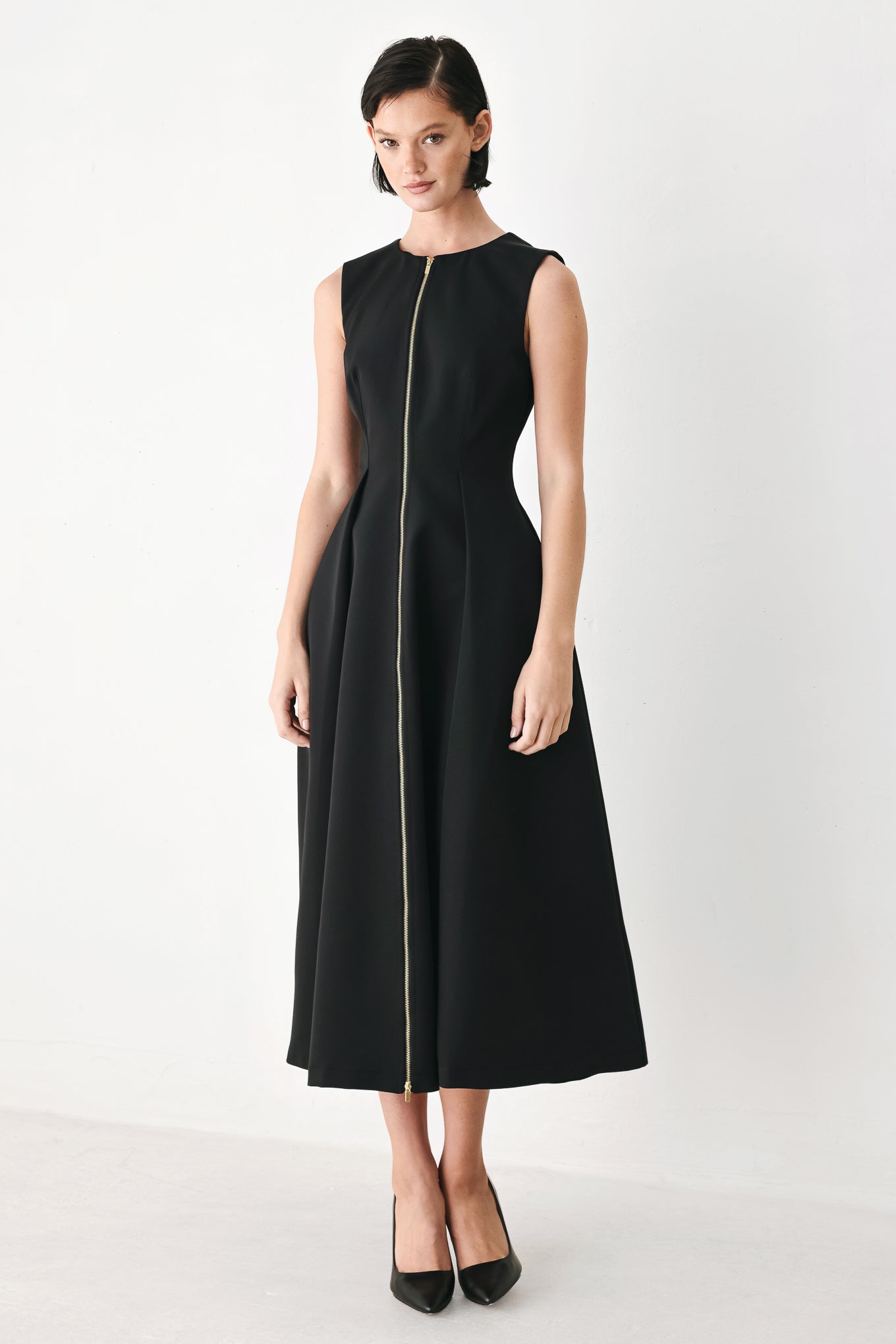 A woman modeling a sleeveless black midi dress with a prominent gold front zipper | FREEMARKET