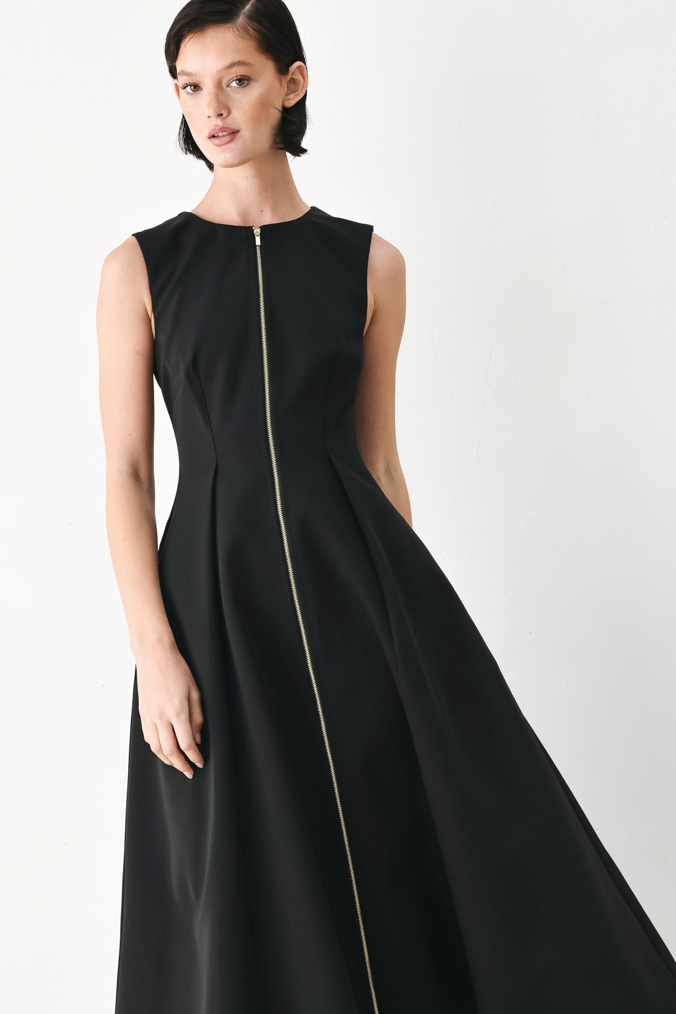 A woman modeling a sleeveless black midi dress with a prominent gold front zipper | FREEMARKET