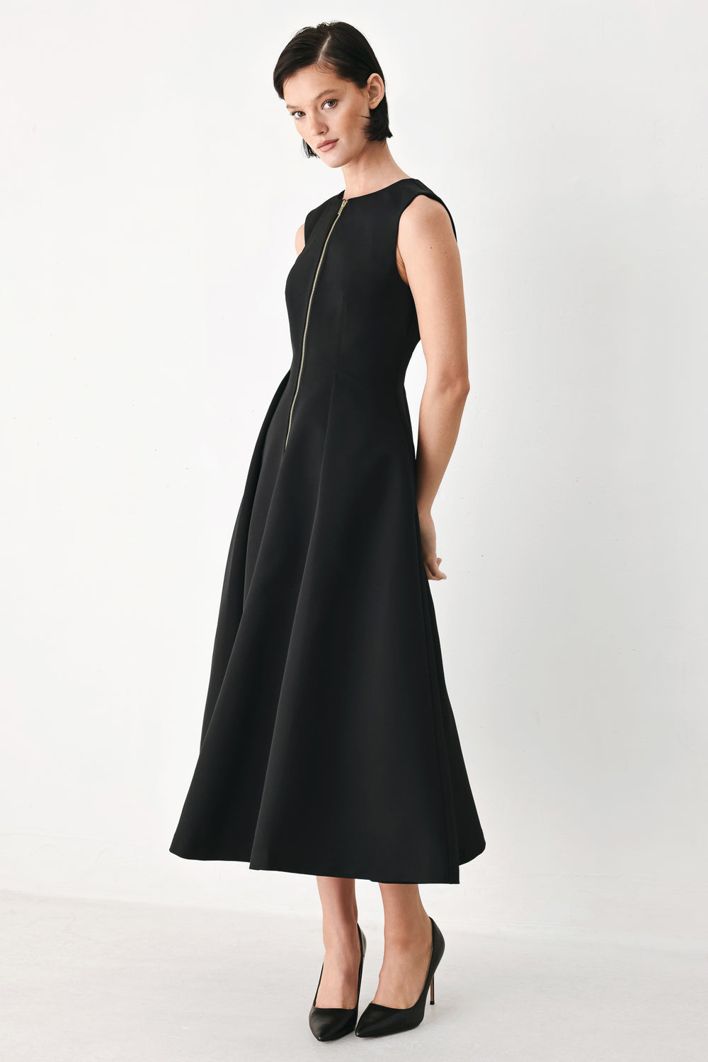 A woman modeling a sleeveless black midi dress with a prominent gold front zipper | FREEMARKET