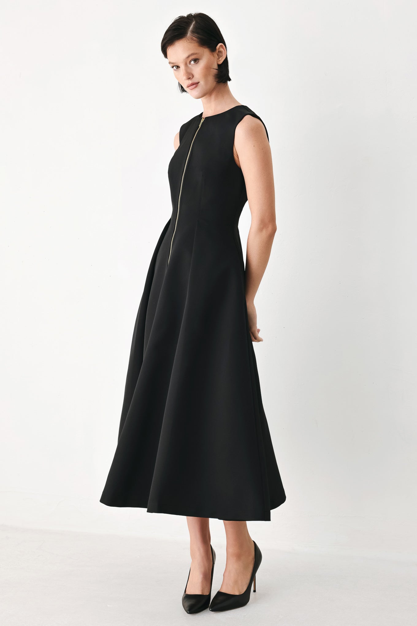 A woman modeling a sleeveless black midi dress with a prominent gold front zipper | FREEMARKET