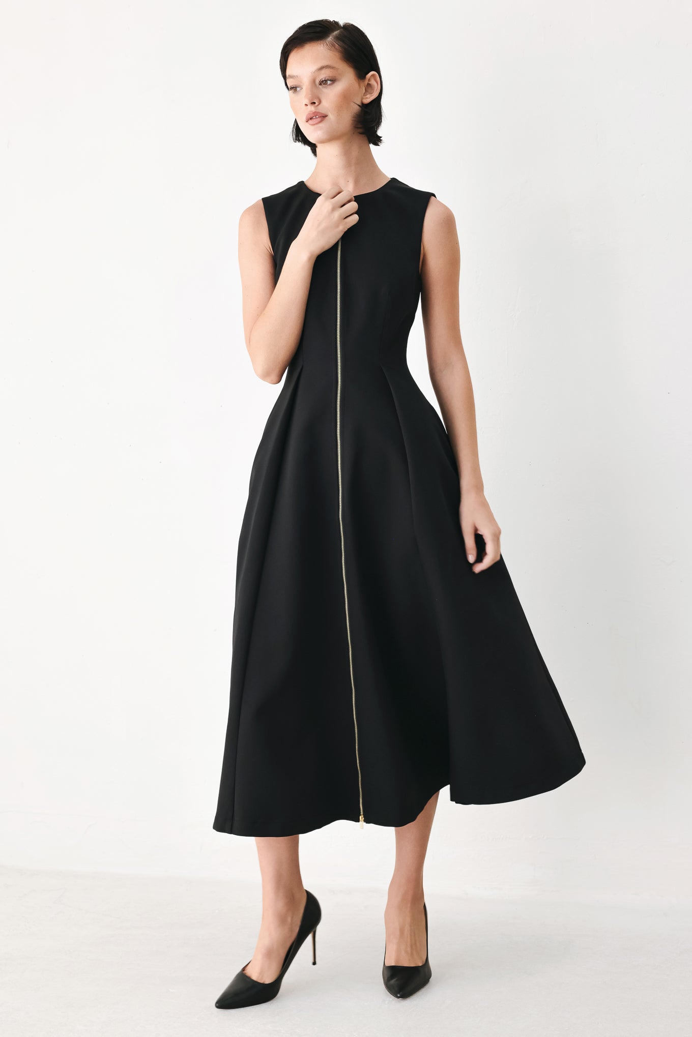A woman modeling a sleeveless black midi dress with a prominent gold front zipper | FREEMARKET