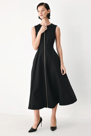 A woman modeling a sleeveless black midi dress with a prominent gold front zipper | FREEMARKET