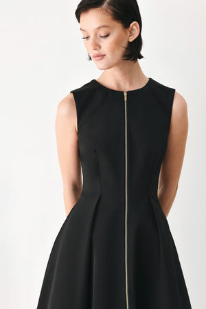 A woman modeling a sleeveless black midi dress with a prominent gold front zipper | FREEMARKET