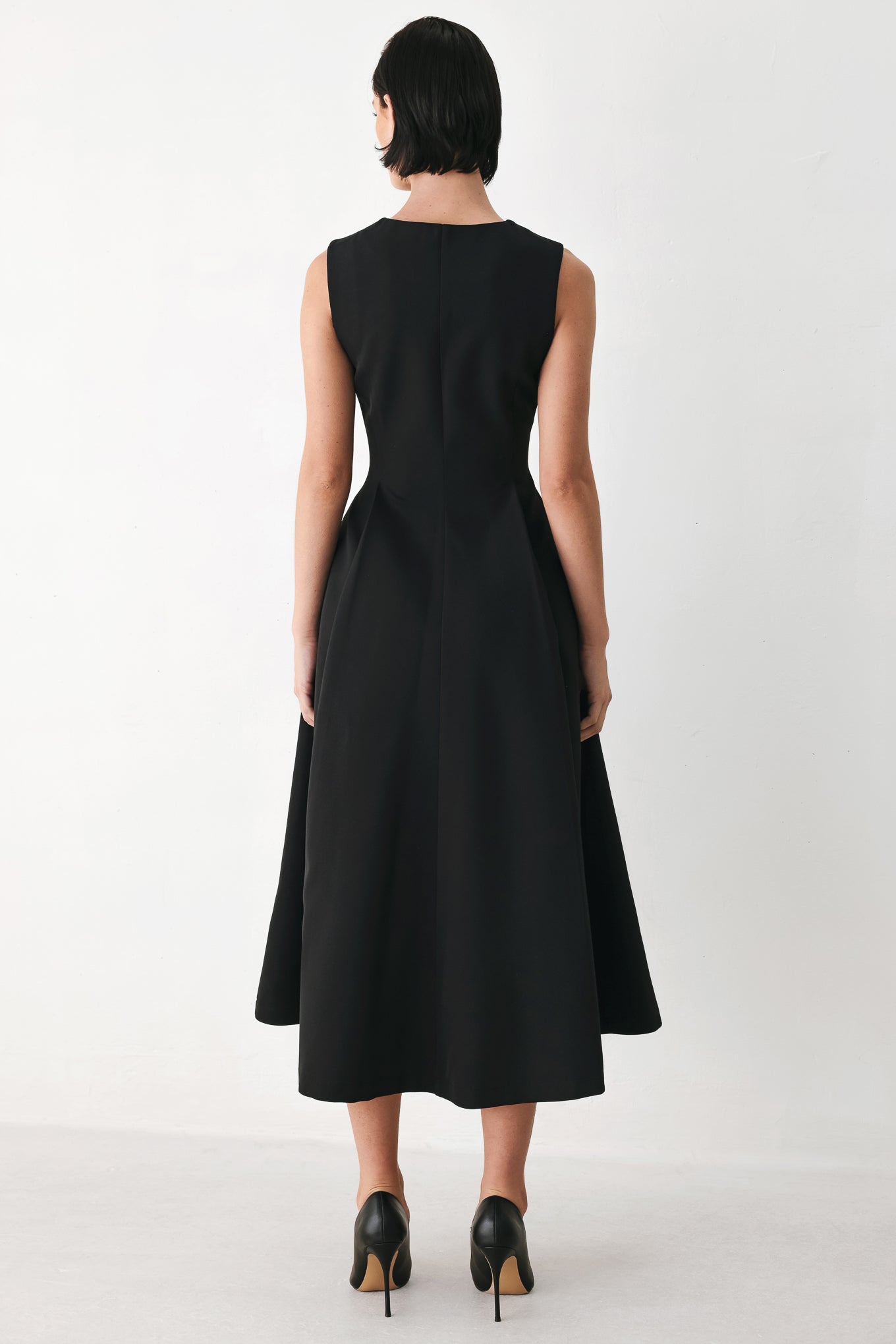A woman modeling a sleeveless black midi dress with a prominent gold front zipper | FREEMARKET