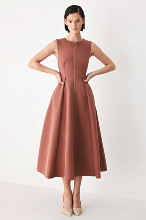 A woman modeling a sleeveless clay rose colored midi dress with a prominent gold front zipper | FREEMARKET