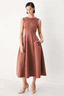 A woman modeling a sleeveless clay rose colored midi dress with a prominent gold front zipper | FREEMARKET