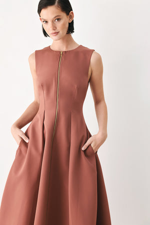 A woman modeling a sleeveless clay rose colored midi dress with a prominent gold front zipper | FREEMARKET