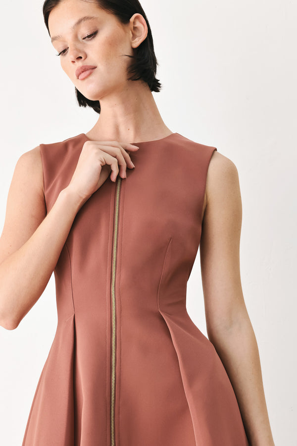 A woman modeling a sleeveless clay rose colored midi dress with a prominent gold front zipper | FREEMARKET
