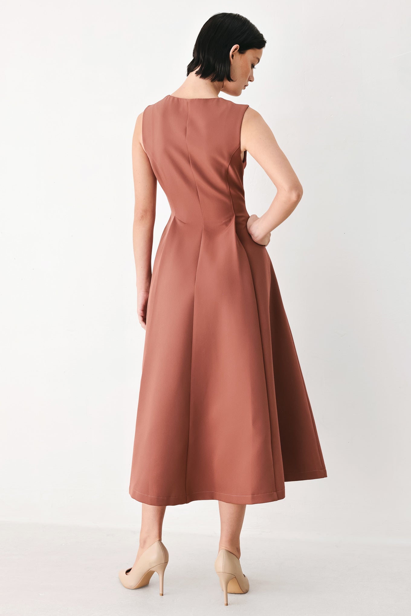 A woman modeling a sleeveless clay rose colored midi dress with a prominent gold front zipper | FREEMARKET