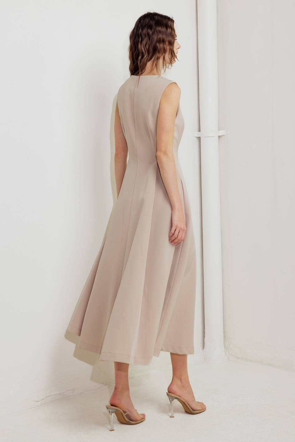 A woman modeling a sleeveless beige midi dress with a prominent gold front zipper | FREEMARKET