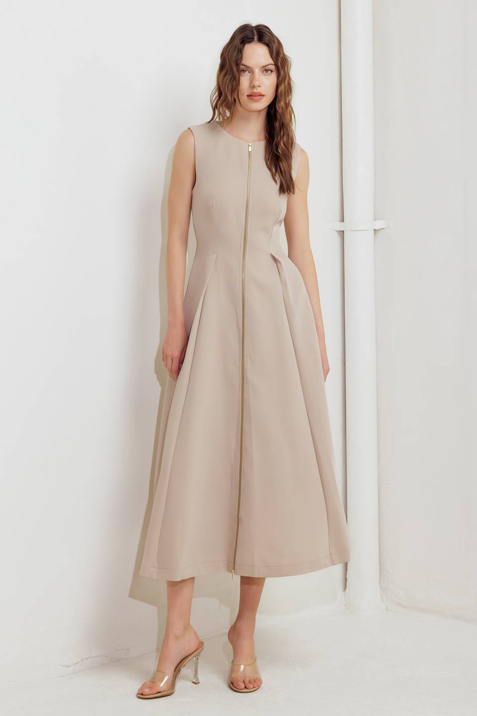 A woman modeling a sleeveless beige midi dress with a prominent gold front zipper | FREEMARKET
