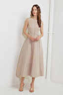 A woman modeling a sleeveless beige midi dress with a prominent gold front zipper | FREEMARKET