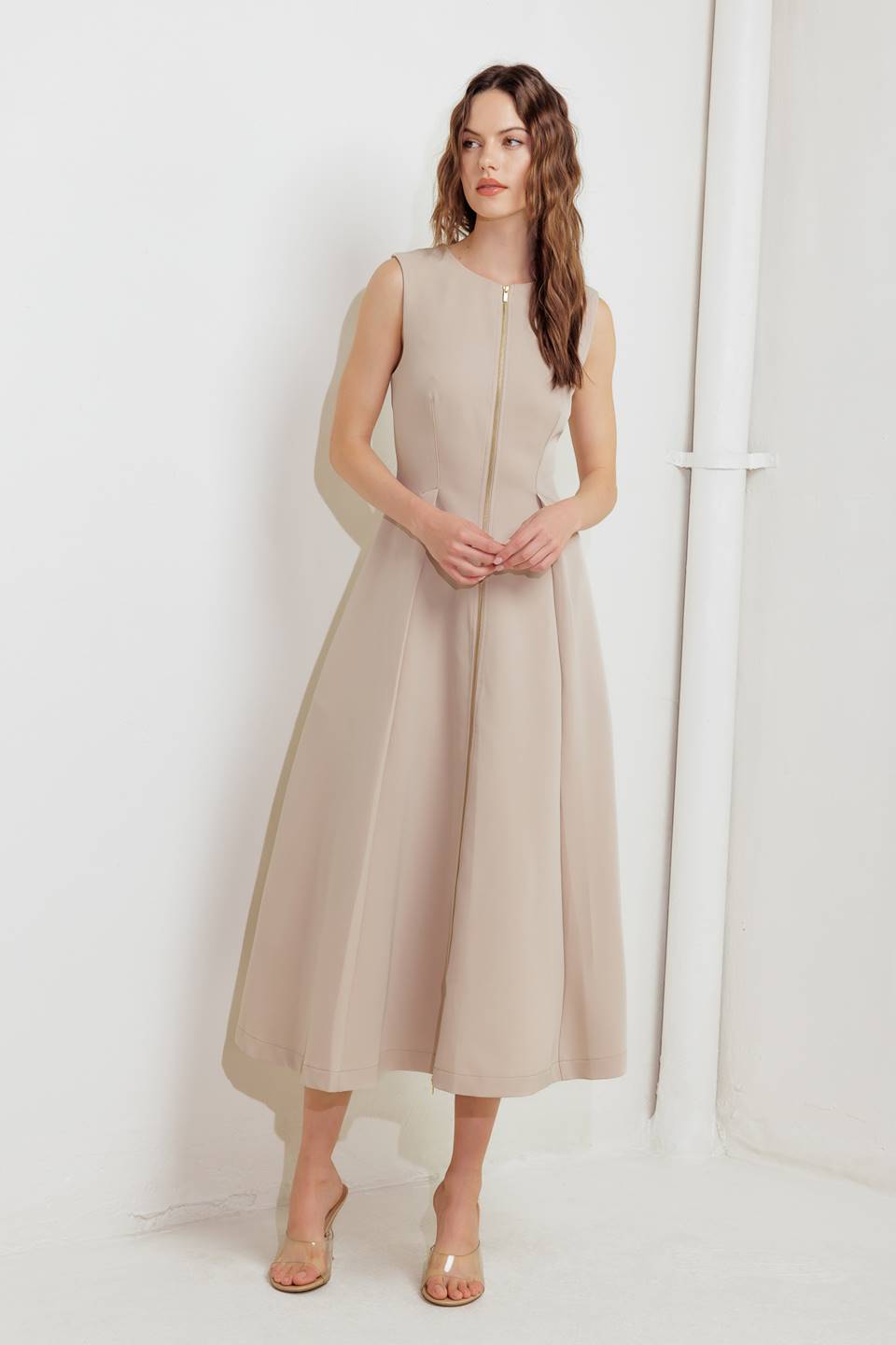 A woman modeling a sleeveless beige midi dress with a prominent gold front zipper | FREEMARKET