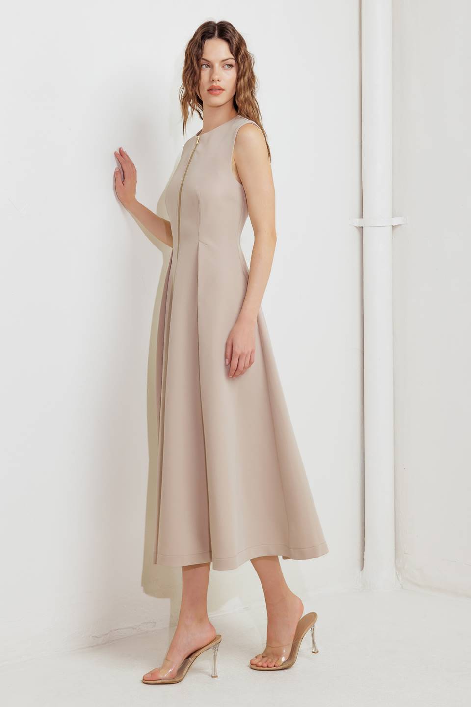 A woman modeling a sleeveless beige midi dress with a prominent gold front zipper | FREEMARKET