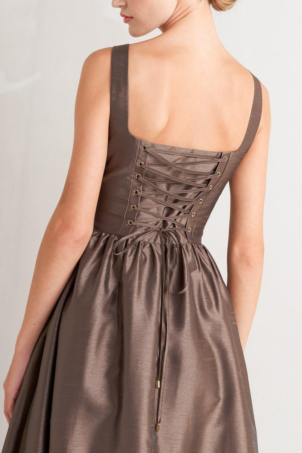 A solid woven midi dress featuring straight neckline, sleeveless, full skirt, back lace up detail and side zipper closure
