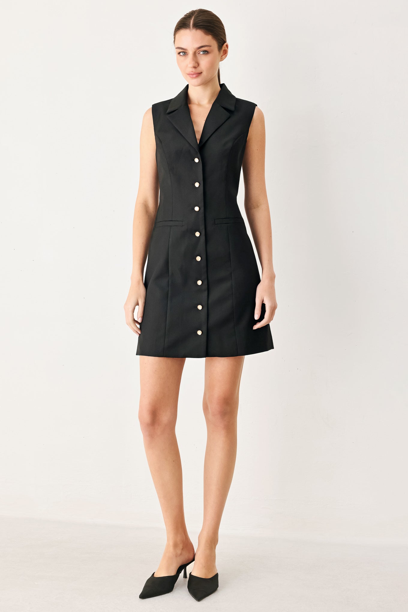 Woman wearing a black sleeveless mini dress featuring blazer collar and front button down | FREEMARKET